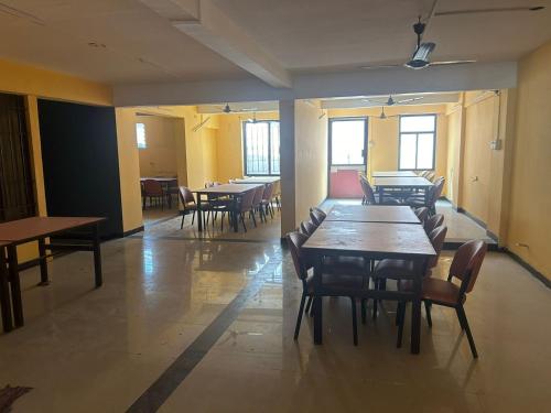 Aishvarya Residency Coimbatore في كويمباتور: غرفة طعام مع طاولات وكراسي ونوافذ