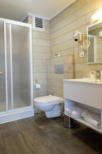 a bathroom with a toilet and a shower and a sink at MB City Hotel in İzmir