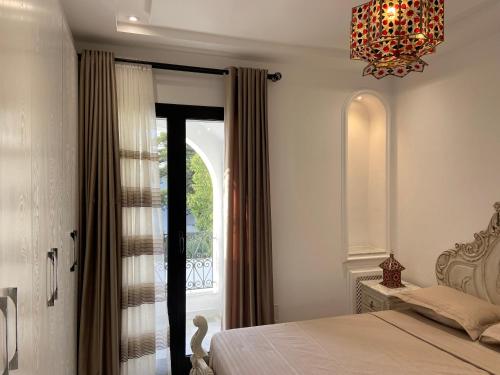 a bedroom with a bed and a window and a chandelier at Marsa-Sidi Bousaid Cosy Authentic Apartment in La Marsa