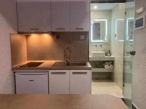 a kitchen with white cabinets and a sink and a mirror at Armeno Studios in Limenaria