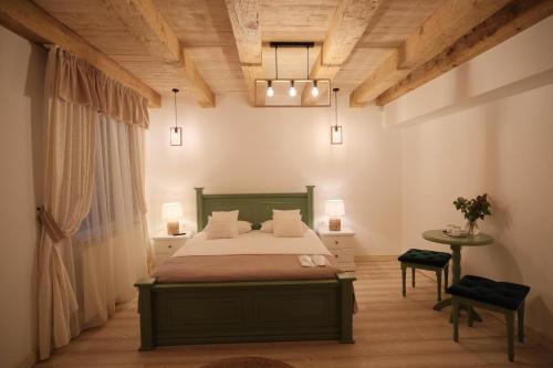 ein Schlafzimmer mit einem grünen Bett und einem Tisch in der Unterkunft Pensiune Agroturistica Molidu in Almaş