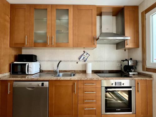 a kitchen with wooden cabinets and a sink at Preciosas vistas en el corazón de la Riveira Sacra in Quiroga