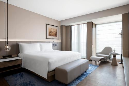 a bedroom with a large white bed and a chair at JW Marriott Shanghai Fengxian in Shanghai