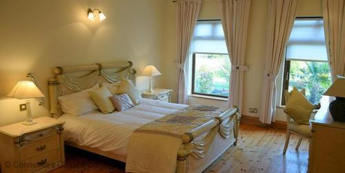 a bedroom with a large bed and two windows at Cleggan 318 Atlantic Lodge in Cleggan