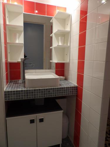 La salle de bains est pourvue d'un lavabo et de carrelage rouge et blanc. dans l'établissement Appart mezzanine avec balcon Piscine, à Saint-Cyprien