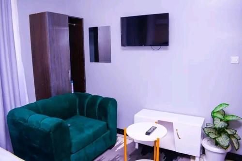 a living room with a green chair and a tv at BELCH Studio Apartment in Kisumu