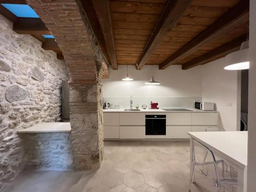 - une cuisine avec des placards blancs et un mur en pierre dans l'établissement Charme in Centro with private parking, à Ascoli Piceno