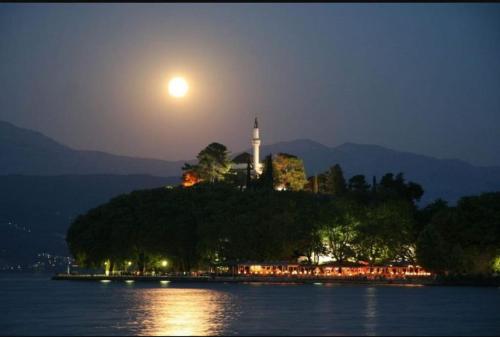 a lighthouse on an island in the water at night at Nikola's apartments_King Pyrros in Palio Limani