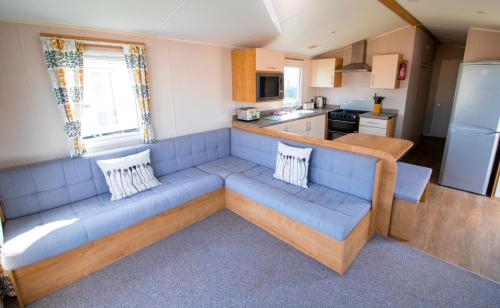 a living room with a blue couch in a kitchen at WW265 Camber Sands Holiday Park in Camber