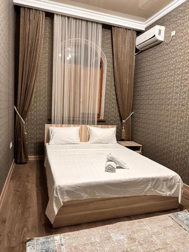 a bedroom with a large bed with white sheets at STATUS in Shymkent