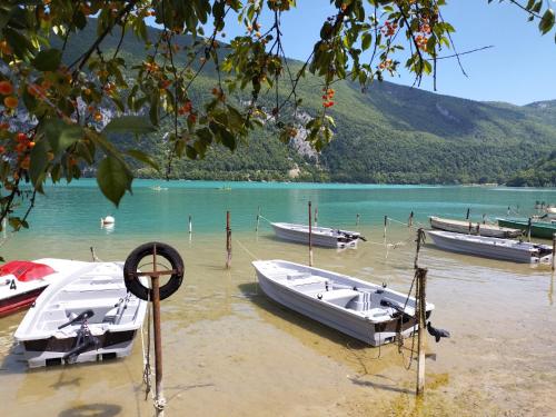 un groupe de bateaux assis sur la rive d'un lac dans l'établissement Camping Le Hameau Des Pécheurs, à Novalaise