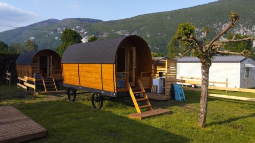 una casa pequeña sentada en el césped junto a una cabaña en Camping Le Hameau Des Pécheurs, en Novalaise