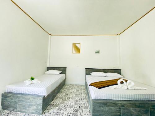 Duas camas num quarto com paredes brancas em เป็นต่อ รีสอร์ต em Ban Kluk Faeb