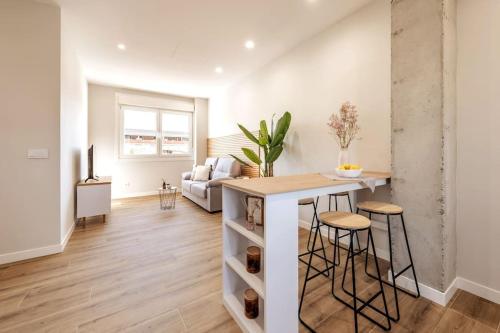 eine Küche und ein Wohnzimmer mit einer Theke und Stühlen in der Unterkunft Apartamento White Tree by Arca Camelia in O Pedrouzo