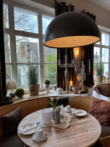 uma mesa num quarto com um grande candeeiro e janelas em Hotel an der Burg em Gießen