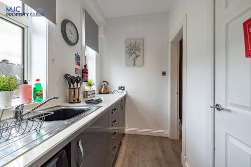 a kitchen with a sink and a clock on the wall at River Teviot in Hawick