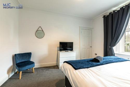 a bedroom with a bed and a chair and a television at River Teviot in Hawick