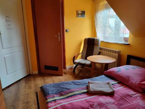 a bedroom with a bed and a chair and a table at Lwi dworek LD in Jarosław