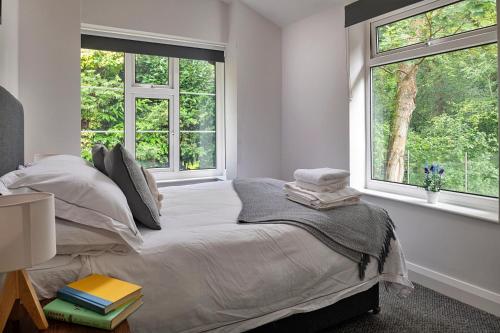 a white bedroom with a bed with two windows at Finest Retreats - Nant Cottage in Llangelynin