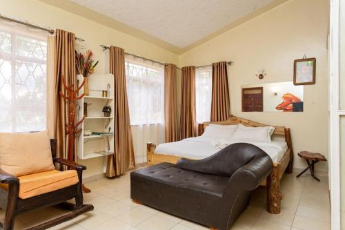1 dormitorio con 1 cama y 1 silla en GIGIRI DRIVE::2BR EXQUISITELY FURNISHED PENTHOUSE en Nairobi