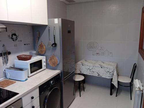 a kitchen with a microwave and a table with chairs at Los acebos. Mar, montaña, cuevas in Rasines