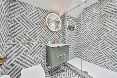 un bagno con carta da parati geometrica grigia e bianca di 1 Bake Cottage Serenity - Premium Coastal Retreat in Looe, Cornwall a Looe