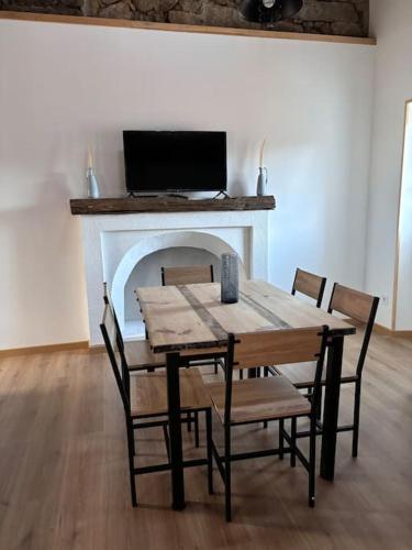 une table à manger avec des chaises et une cheminée dans l'établissement chez lulu Appartement cosy., à Cozzano