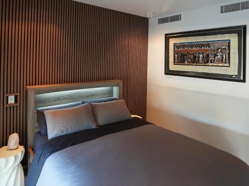 a bedroom with a bed with a wooden wall at Harbour-view Waterfront Apartment in Darwin