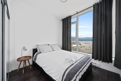 1 dormitorio con cama y ventana grande en Bright and Modern Suite with Amazing views!, en Vancouver