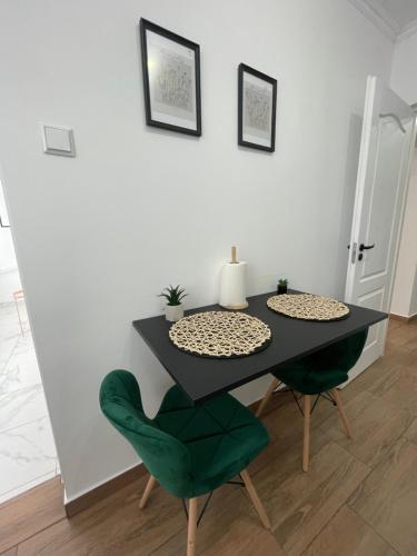 een eettafel met 2 groene stoelen en een tafel bij Apartament Central in Onești