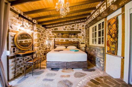 a bedroom with a bed in a room with stone walls at Roxani Aqua Bliss - Serene Garden Getaway in Evkarpía