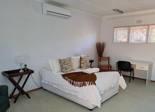 ein weißes Schlafzimmer mit einem Bett und einem Schreibtisch in der Unterkunft The Golden Grape B&B in Lutzville