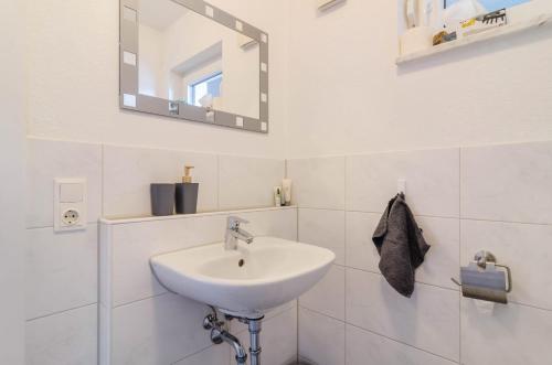 a white bathroom with a sink and a mirror at Ferienwohnung Inzigkofen in Inzigkofen