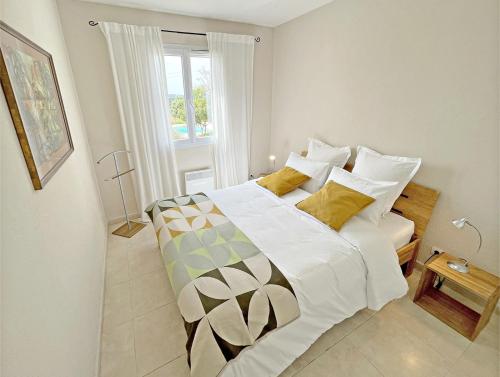une chambre avec un lit avec des draps blancs et des oreillers jaunes dans l'établissement Villa Parpaiouns - confortable maison avec piscine privée chauffée en Provence, à Entrecasteaux