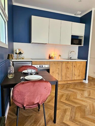 une cuisine avec une table et deux chaises et une cuisine avec des placards blancs dans l'établissement Appartement Le Bd Haussmann, chic & raffiné !, à Cholet