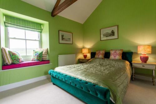 a green bedroom with a bed and two windows at Lowtown Cottage in Brampton