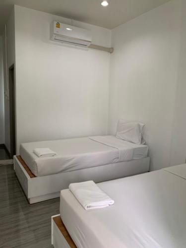a white room with two beds and a fan at กิจตรงวิลล์ รีสอร์ท Kittrongvill in Ubon Ratchathani