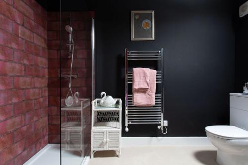 a bathroom with black walls and a shower with towels at Lowtown Cottage in Brampton