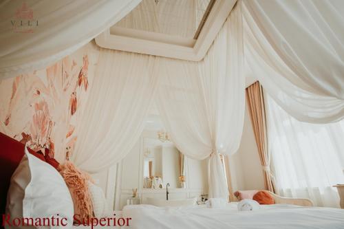 a bedroom with white curtains and a large bed at Vili Apartments in Oradea