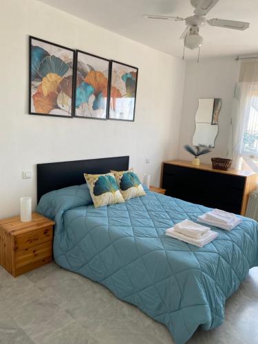een slaapkamer met een blauw bed met 2 kussens bij Apartamento La cala 2 in Cala del Moral