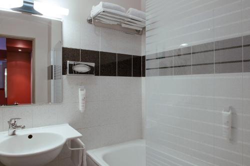 a white bathroom with a sink and a mirror at The Originals City, Hôtel Ascotel, Lille Est Grand Stade in Villeneuve d'Ascq