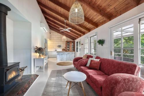 a living room with a red couch and a fireplace at Jamieson Cottages - Cottage Four - Sleeps 4 in Howqua