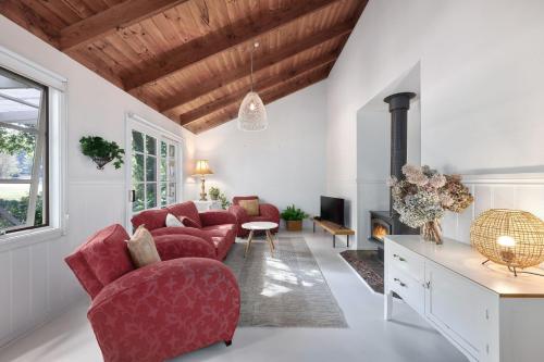 a living room with red chairs and a fireplace at Jamieson Cottages - Cottage Four - Sleeps 4 in Howqua