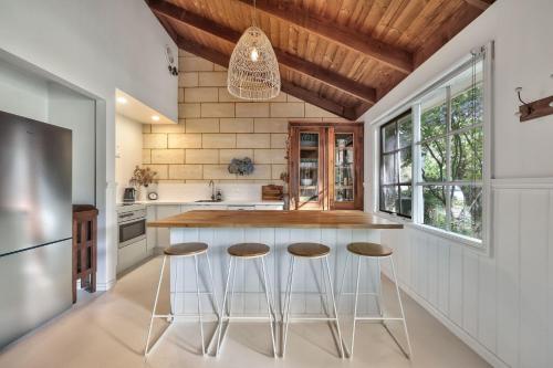 a kitchen with white counter tops and stools at Jamieson Cottages - Cottage Four - Sleeps 4 in Howqua