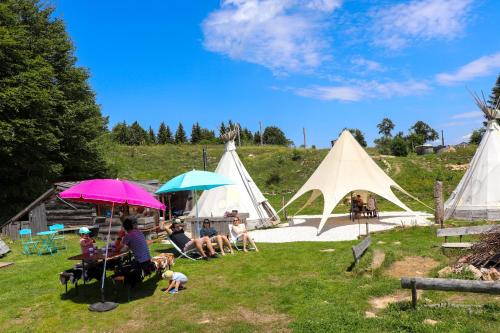 een groep mensen die onder paraplu's in een veld zitten bij Village Tipi in La Féclaz
