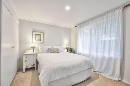 a white bedroom with a bed and a window at Jamieson Cottages - Cottage Four - Sleeps 4 in Howqua