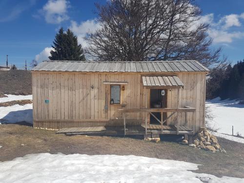um pequeno barracão de madeira com uma porta na neve em Village Tipi em La Feclaz