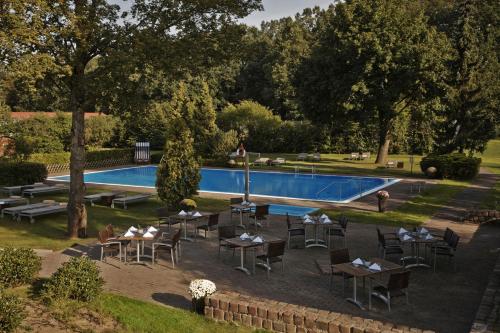 a pool with tables and chairs in front at Kempinski Hotel Frankfurt Gravenbruch in Gravenbruch