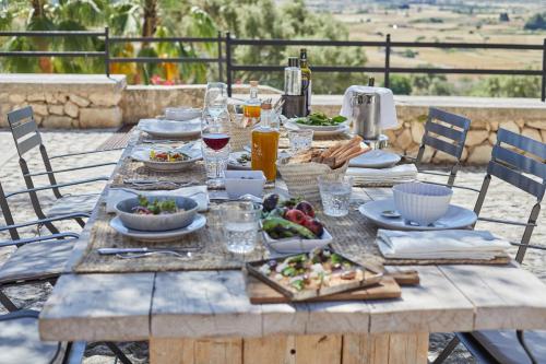 a wooden table with plates of food on it at Finca Serena Mallorca, Small Luxury Hotels in Montuiri