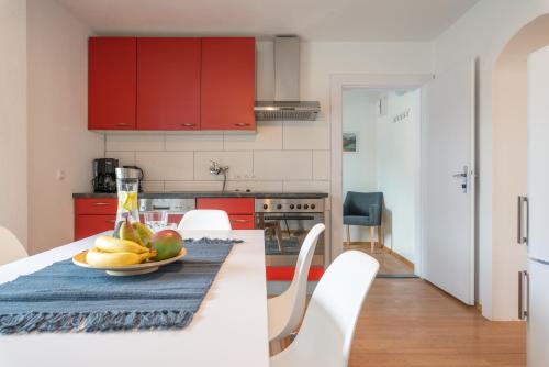 a kitchen with red cabinets and a plate of fruit on a table at Sun Valley Apartments in Maishofen